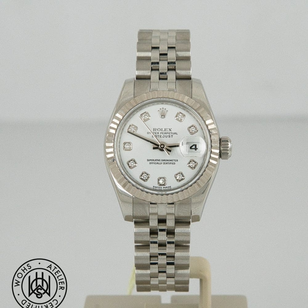 Silver Rolex Datejust wristwatch with a fluted bezel, diamond hour markers, and a date window at 3 o'clock on a white dial.