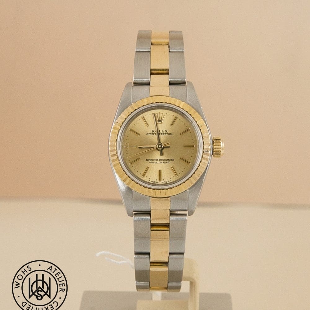 Two-tone Rolex Oyster Perpetual wristwatch on display with a gold bezel and champagne dial.