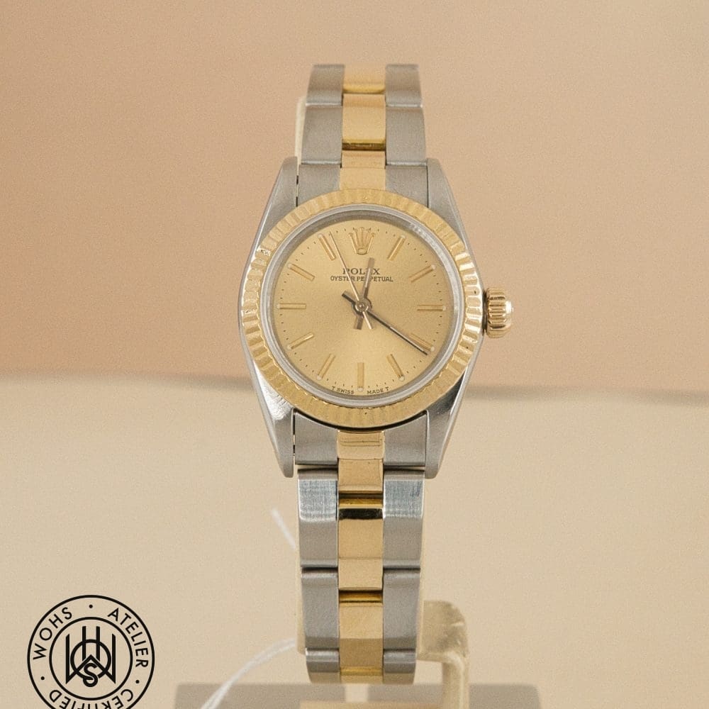 Two-tone Rolex Oyster Perpetual wristwatch on a display stand with a gold bezel and silver bracelet.
