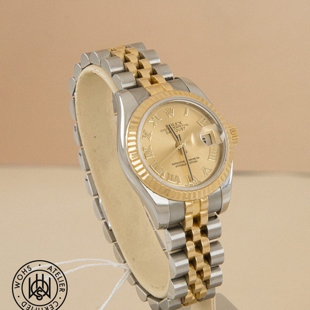 Two-tone Rolex Datejust wristwatch with gold bezel and center links on display, WOHS certificate seal visible in corner. DSC02963