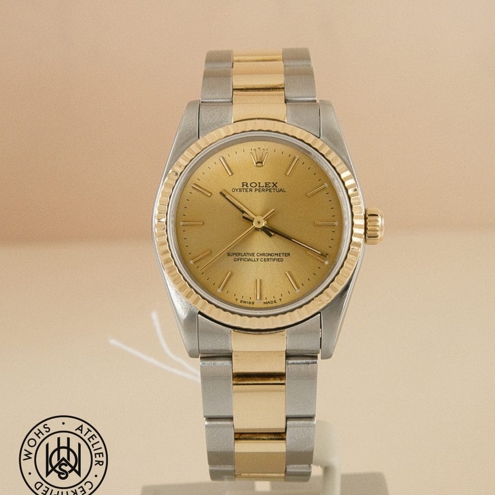 Two-tone Rolex Oyster Perpetual watch with a gold dial and fluted bezel on a display stand. DSC03020