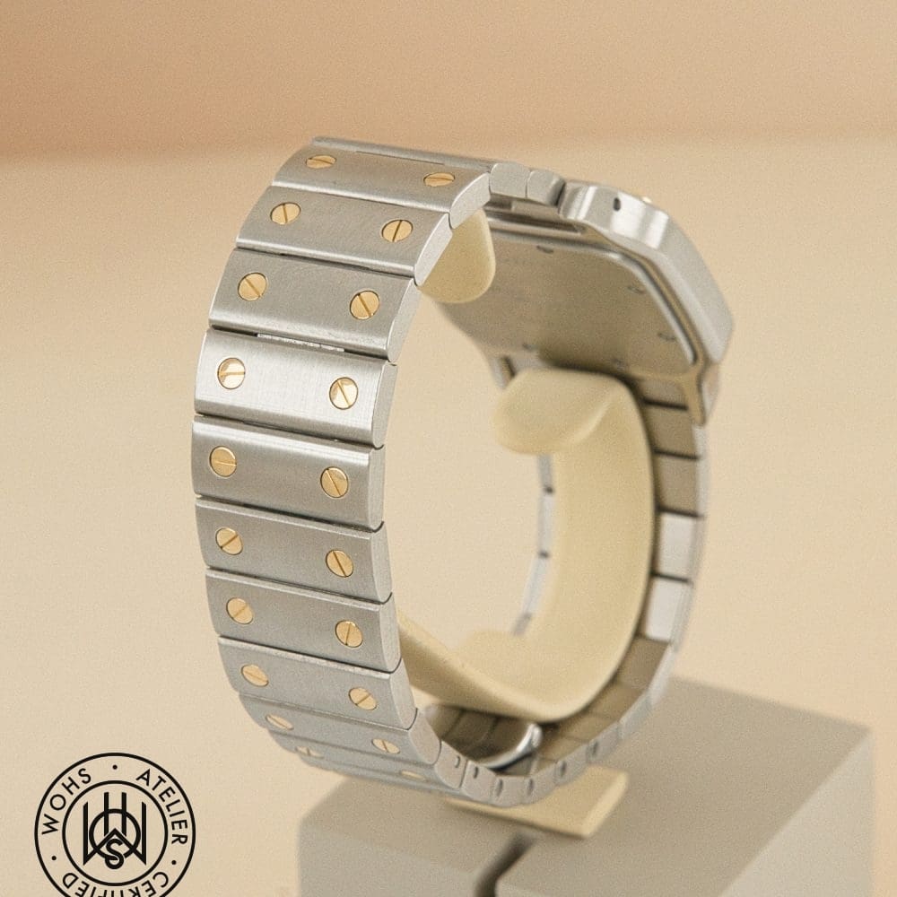 Close-up of a silver metal watch bracelet with gold screws, mounted on a display stand. DSC03078