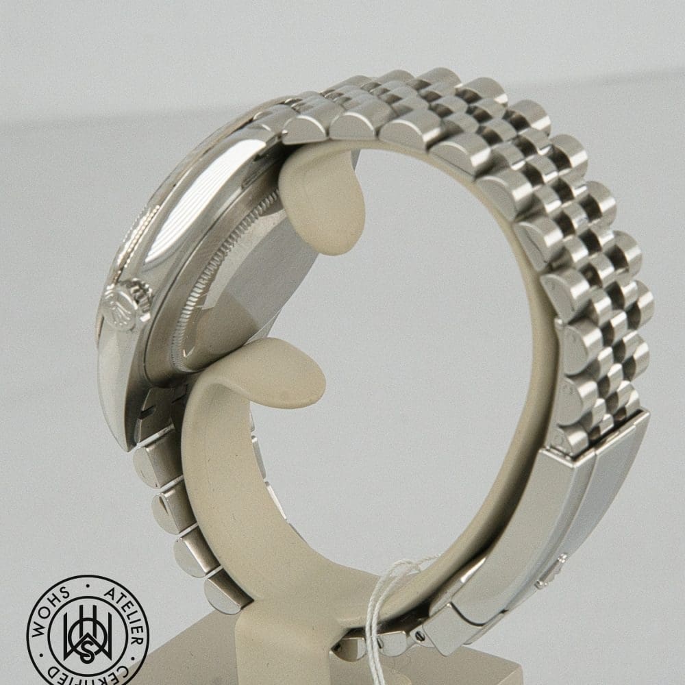 Close-up of a stainless steel wristwatch showing the side with crown and a multi-link bracelet; WOHS Atelier Certified seal in the bottom-left corner. DSC03104