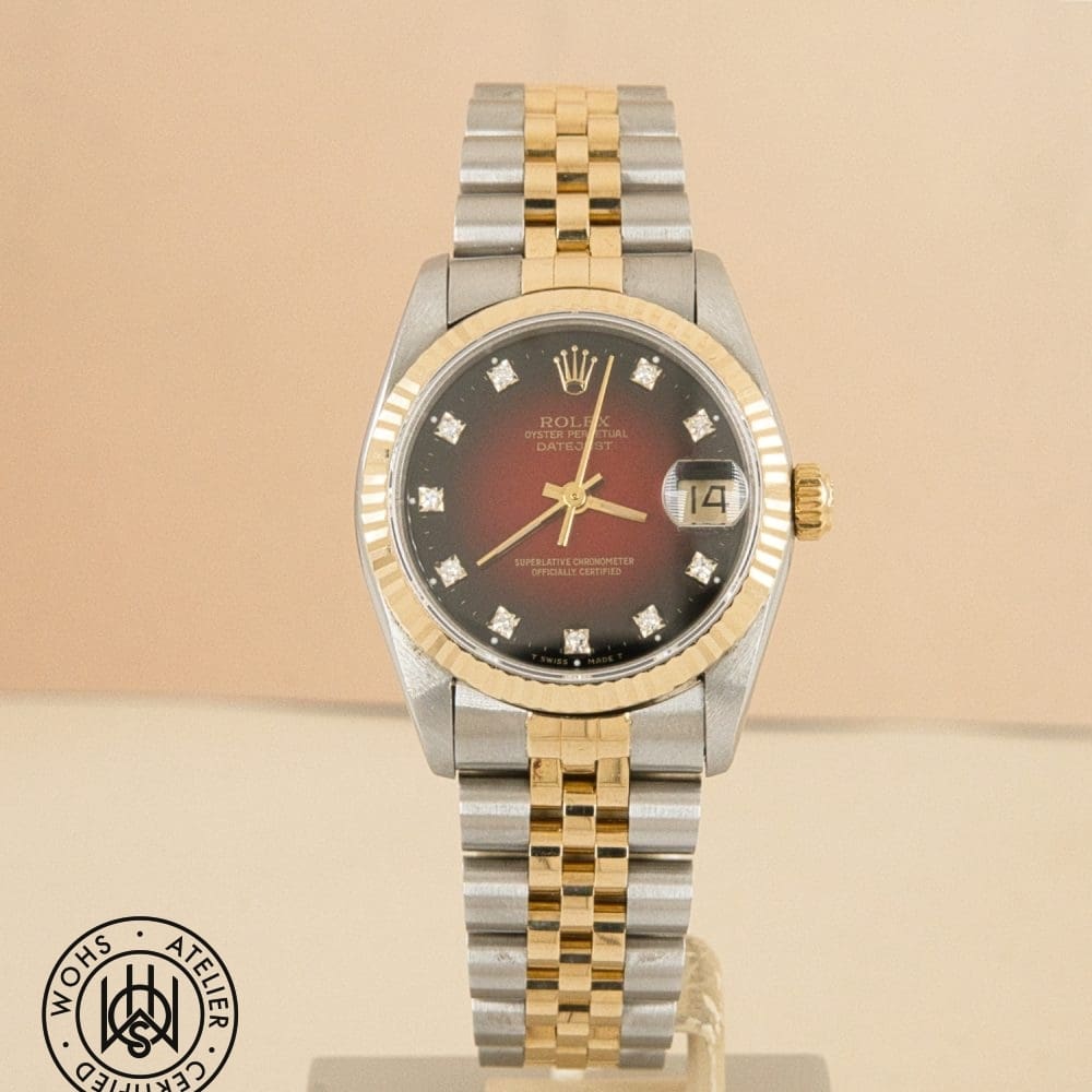 Two-tone Rolex Datejust wristwatch with a red dial, diamond hour markers, and a gold-bezel, bracelet showing gold and silver links.