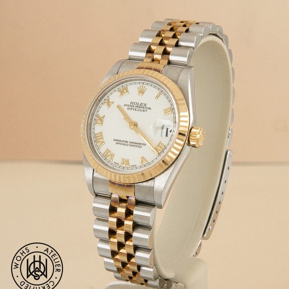 Two-tone Rolex Datejust wristwatch with gold and silver bracelet on a stand, white dial with gold Roman numerals and date window magnifier. DSC03157