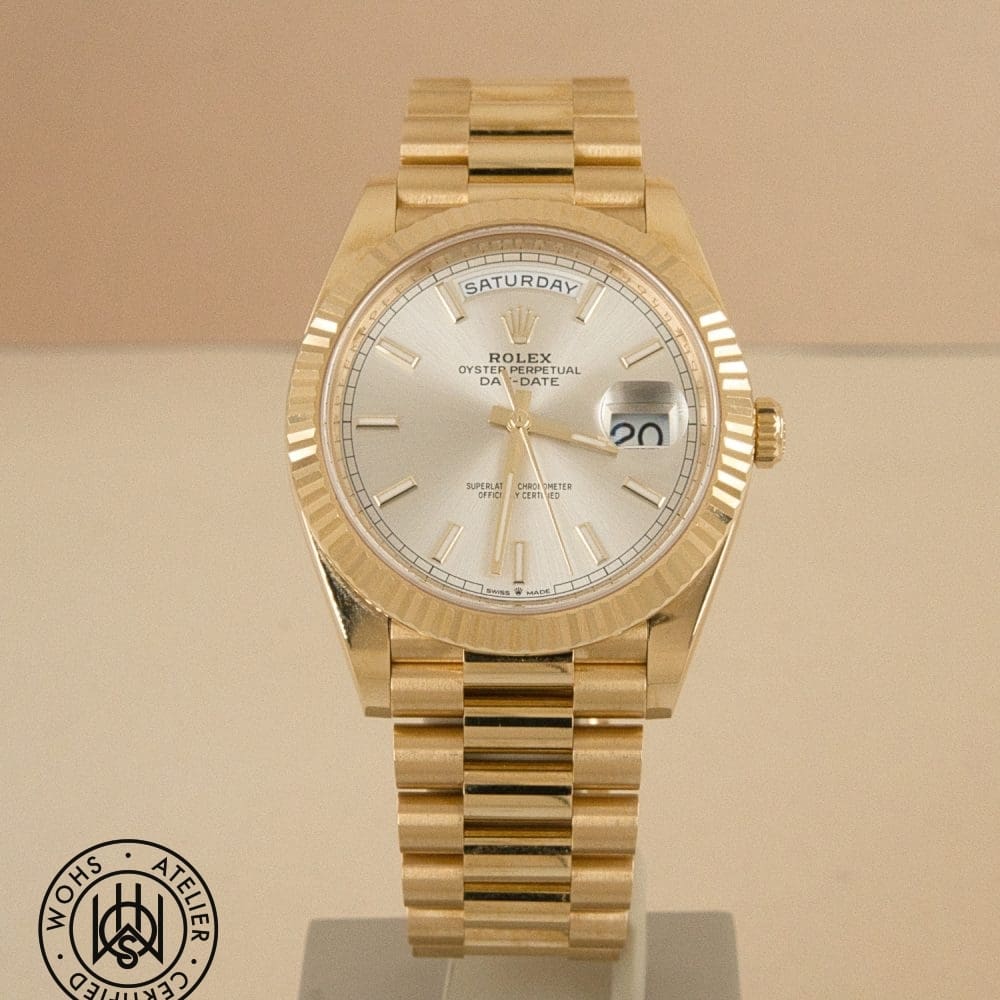 Gold Rolex Oyster Perpetual Day-Date watch on display with a magnified date window at 3 o'clock bar, showing 'SATURDAY' on the day wheel.