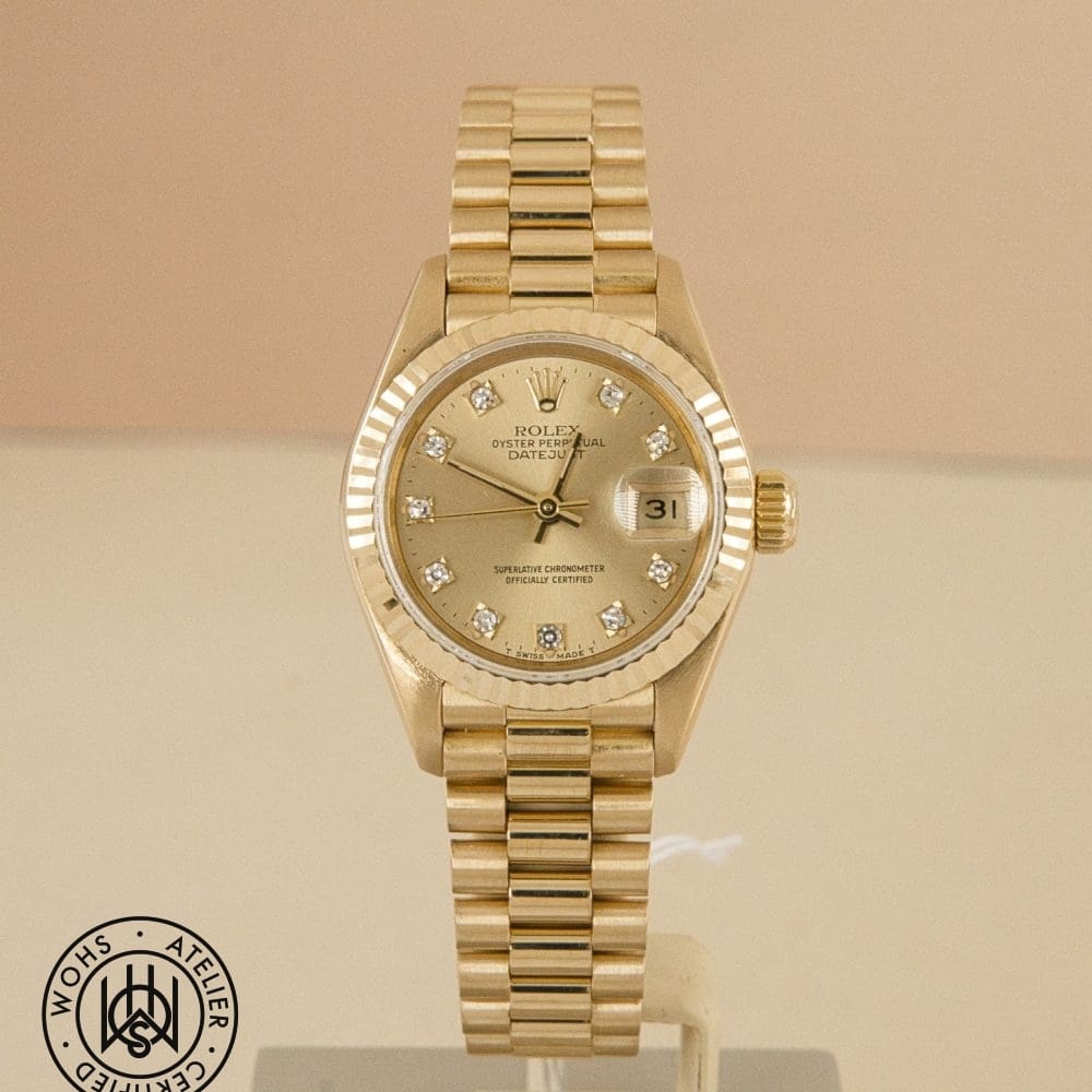 Gold Rolex Datejust wristwatch with diamond hour markers, fluted bezel, and a date window at 3 on a gold bracelet in display
