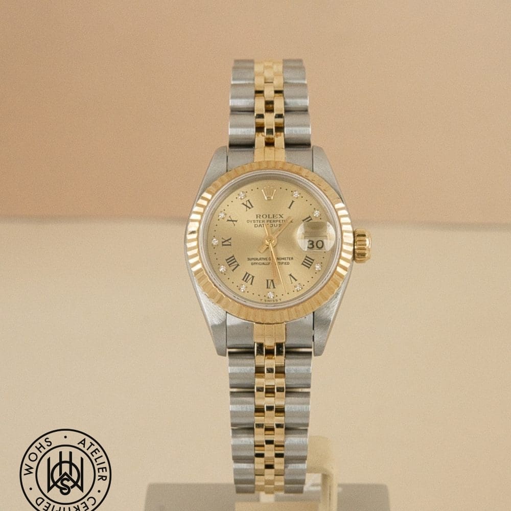 Two-tone Rolex Datejust wristwatch with gold bezel and bracelet on display; watermark stamp bottom left.