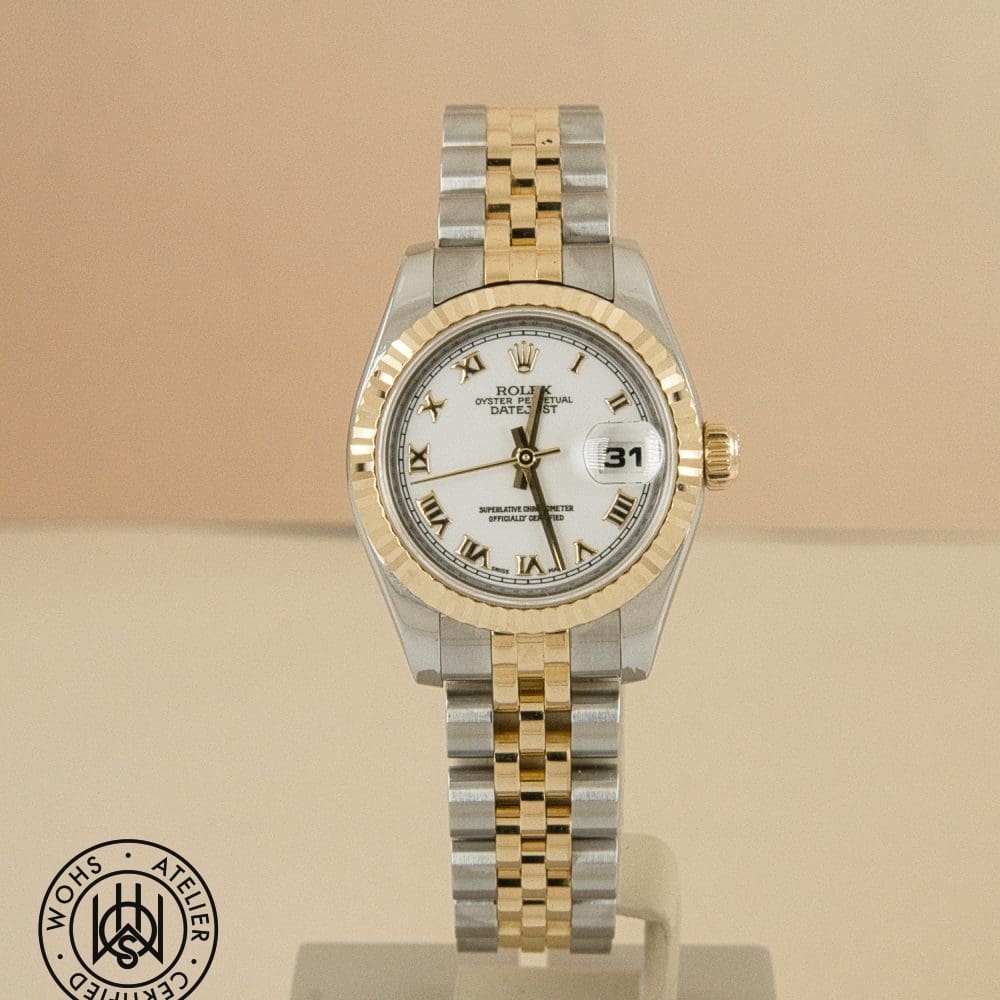 Two-tone Rolex Datejust watch on display with gold and stainless-steel bracelet, white dial, Roman numerals, and a date window at 3 o'clock