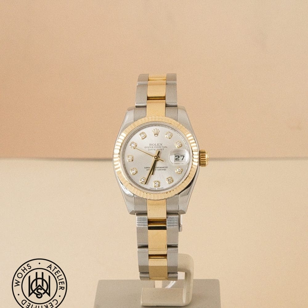 Two-tone Rolex Datejust watch on display, gold bezel, silver dial with diamond hour markers and date window at 3 o'clock.