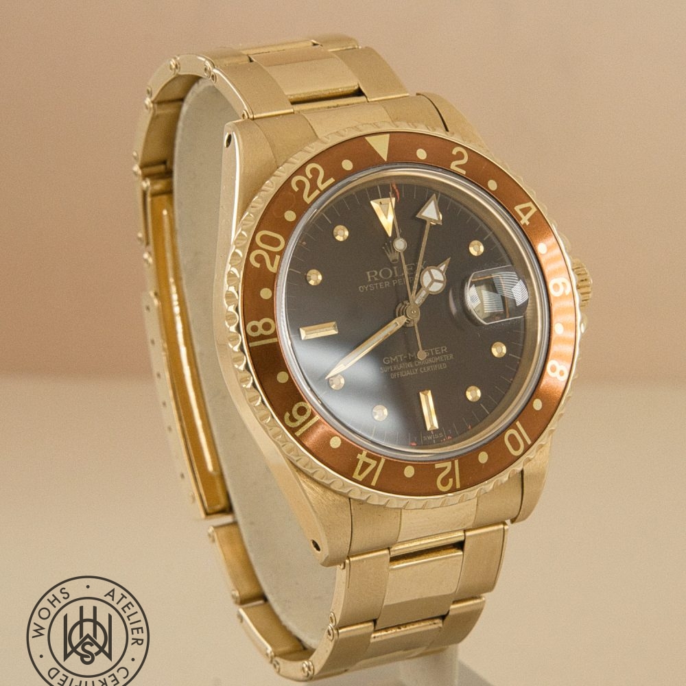 Gold Rolex GMT-Master wristwatch with brown 24-hour bezel, black dial, and date magnifier on a display stand DSC03314