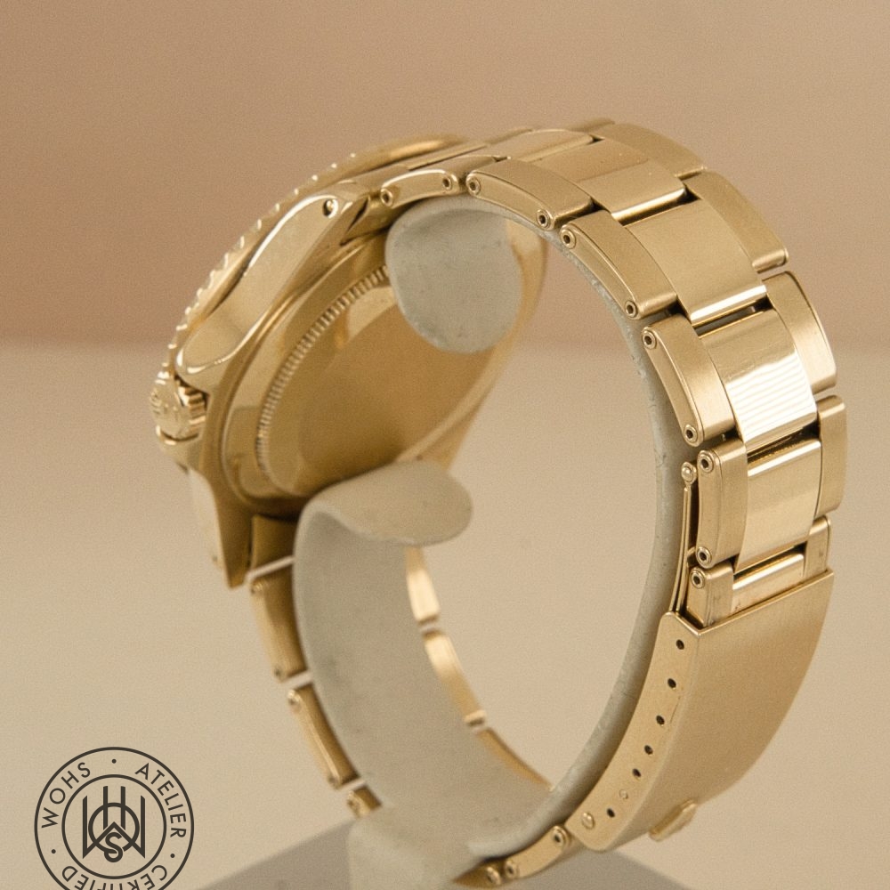 Close-up of a gold metal wristwatch on a display, showing the bracelet and the back of the case from the side view. DSC03316