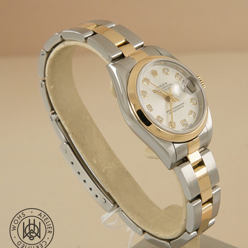 Two-tone Rolex Datejust with diamond hour markers, gold bezel, and stainless steel bracelet on a beige background. Preowned Rolex Lady Datejust 79163 silver diamond 4