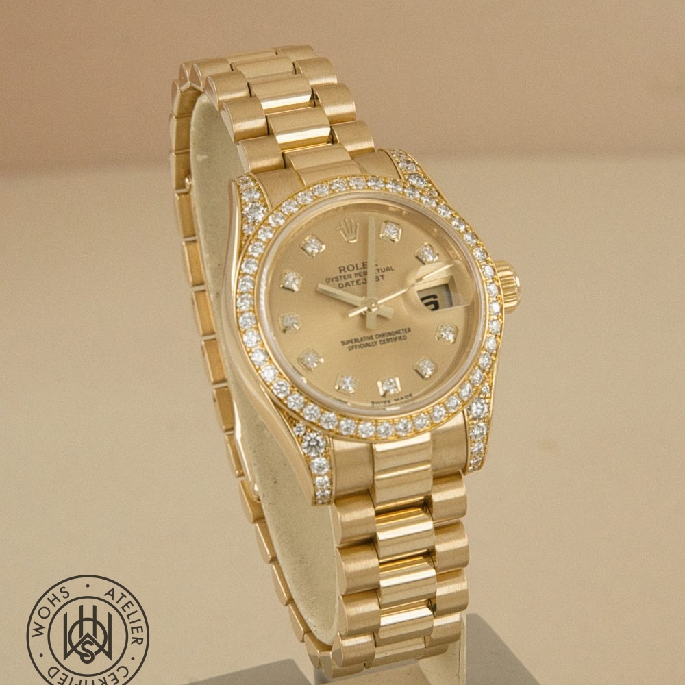 Gold Rolex Datejust watch with diamond-studded bezel and dial markers, on a display stand; includes date window with magnifier and a bottom-left circular certification stamp. Preowned Rolex Lady Datejust reference 179158 factory set lugs and bezel 3