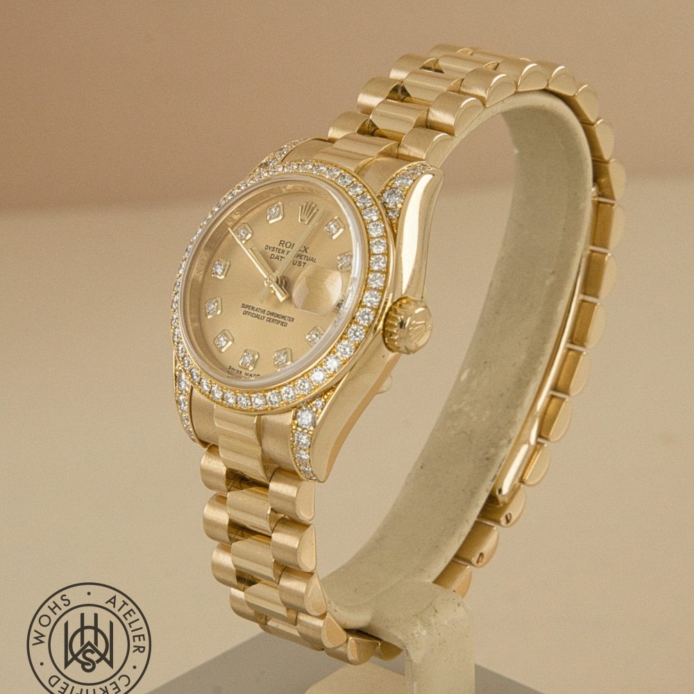 Gold Rolex Datejust wristwatch with diamond-encrusted bezel and diamond hour markers on a display stand. Preowned Rolex Lady Datejust reference 179158 factory set lugs and bezel 7