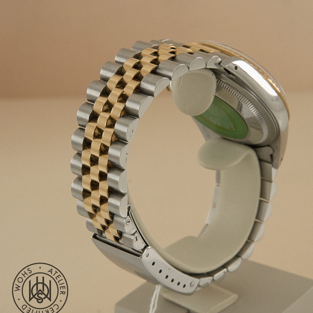 Two-tone metal watch bracelet (gold and silver links) curved on a display stand with a round logo watermark in the corner, viewed from the side. Rolex Datejust 36mm reference 16233 4