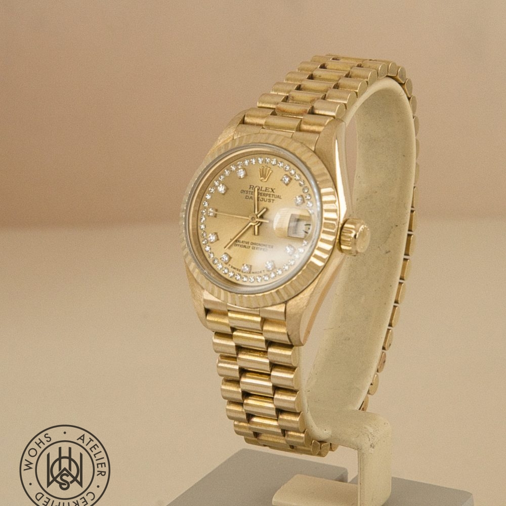 Gold Rolex wristwatch with a diamond-studded bezel on a display stand. Rolex Ladies Datejust 26mm 69178 Diamond Hour and Pave set markers 18ct dial 1