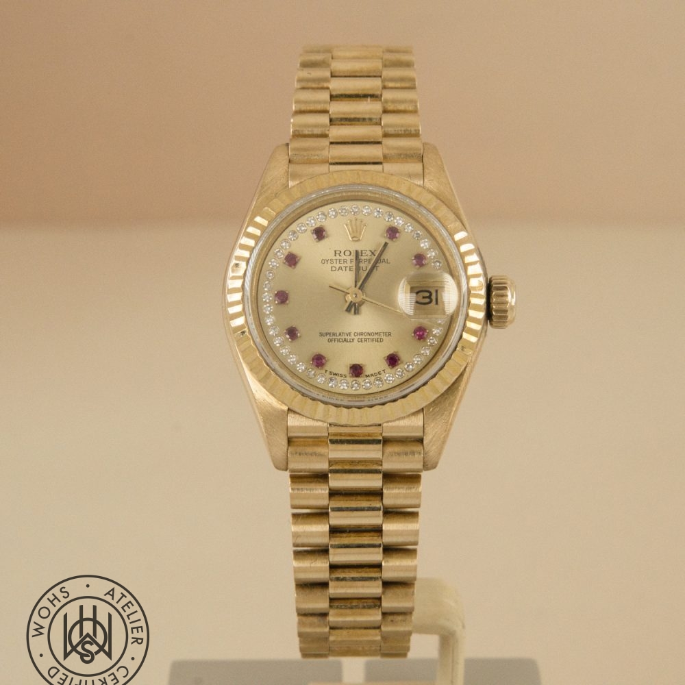 Gold Rolex Datejust wristwatch with diamond-studded bezel and ruby hour markers on a metal bracelet, showing the date at 3 o'clock with magnifier. Rolex Ladies Datejust reference 69178 - Diamond and Ruby Dial Pave 18ct Gold Dial 2