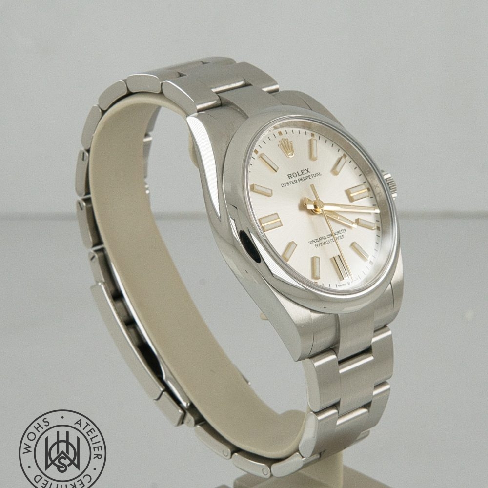 Rolex Oyster Perpetual silver watch with gold markers on a metal bracelet, angled view, watermark visible in corner (informative). Rolex Oyster Perpetual Pre-Owned reference 134300 41mm silver dial box papers 2025 4
