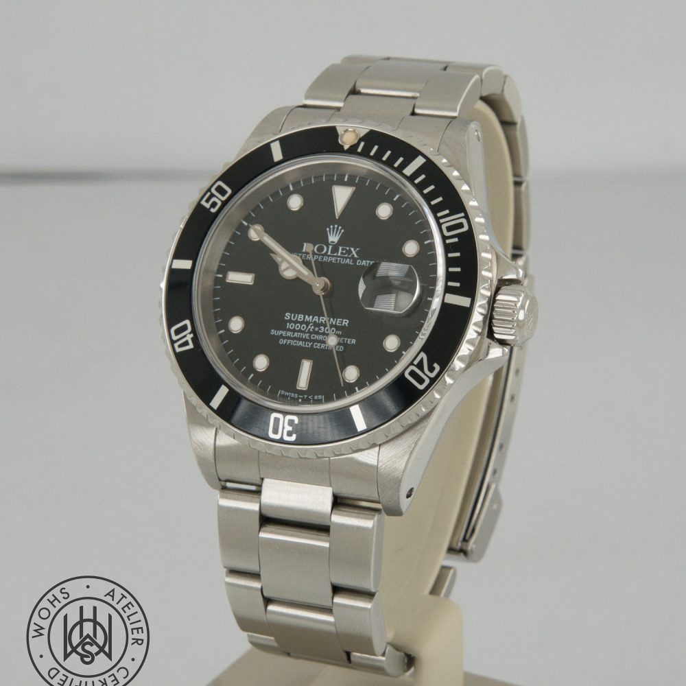 Stainless steel Rolex Submariner watch with black bezel and dark dial, showing date window with cyclops magnifier and prominent hour markers on a metal bracelet. Rolex Submariner reference 16610 preowned 1998 box papers 1