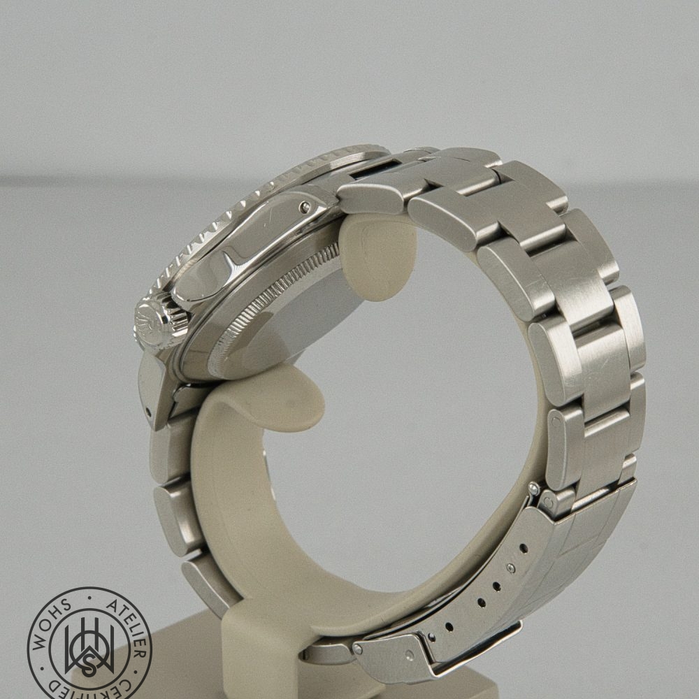 Side view of a stainless steel wristwatch on a display stand, showing crown and textured bezel on the left side of the case. Rolex Submariner reference 16610 preowned 1998 box papers 5