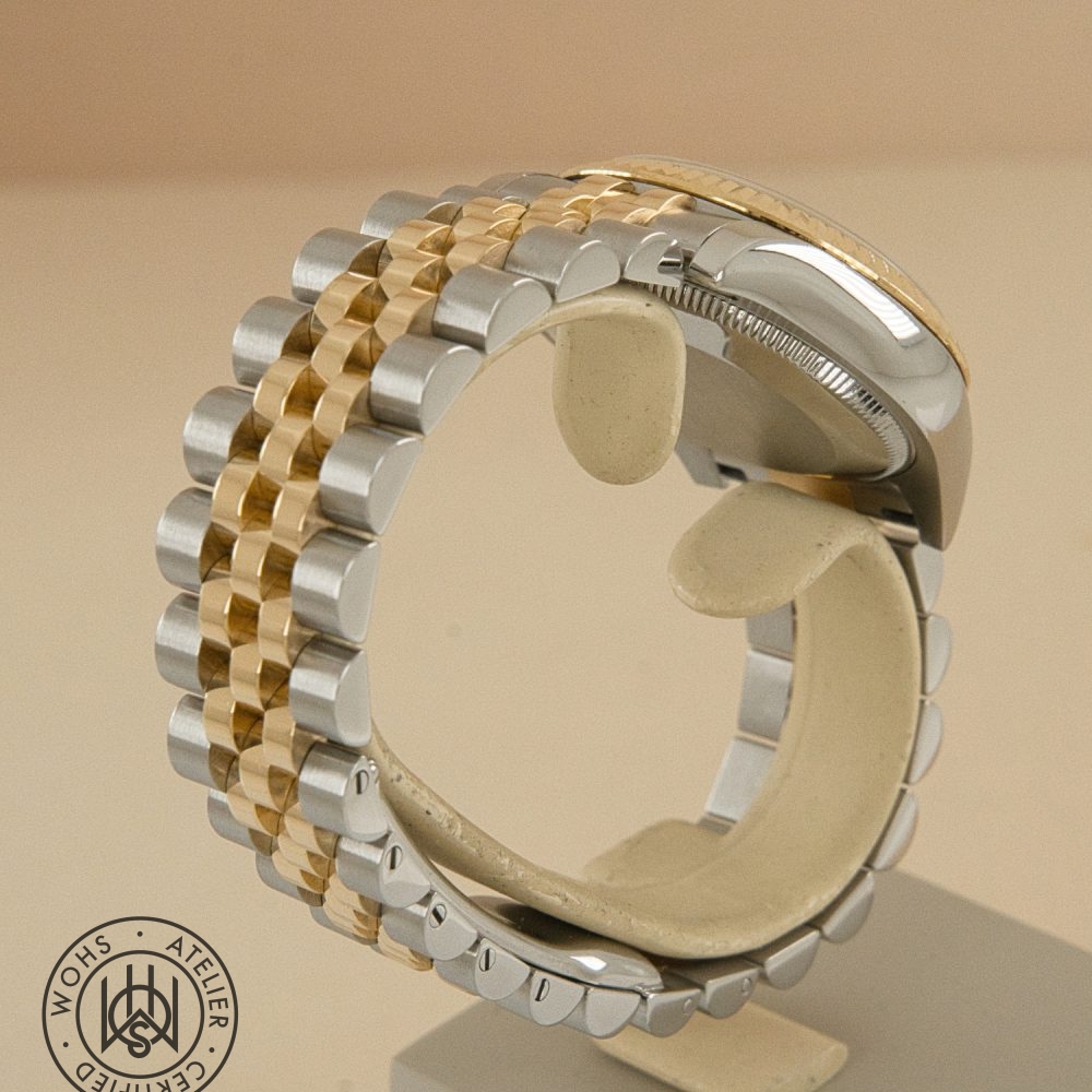 Close-up of a two-tone gold and stainless steel watch bracelet curved on a display stand with a WOHS Atelier Certification seal in the bottom left. Used Ladies Rolex datejust reference 178273 champange diamond dial 5